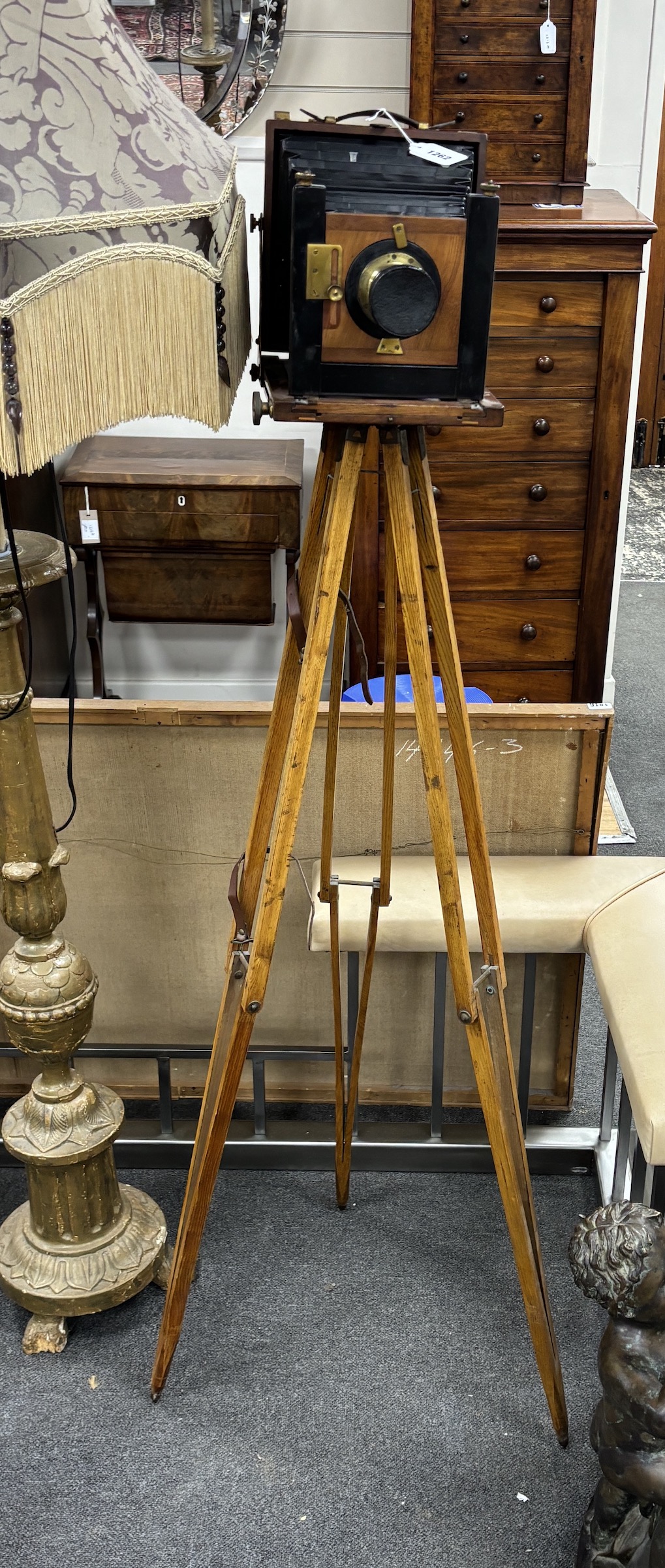 An early 20th century brass and mahogany ‘Challenge’ half plate bellows camera by J. Lizars, Glasgow, with a lens, and on an oak tripod